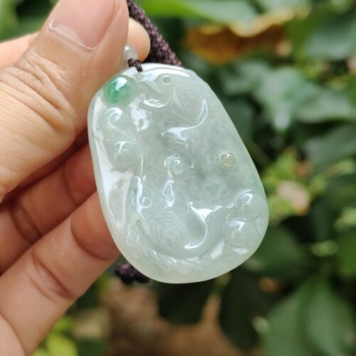 a hand holding a jade pendant