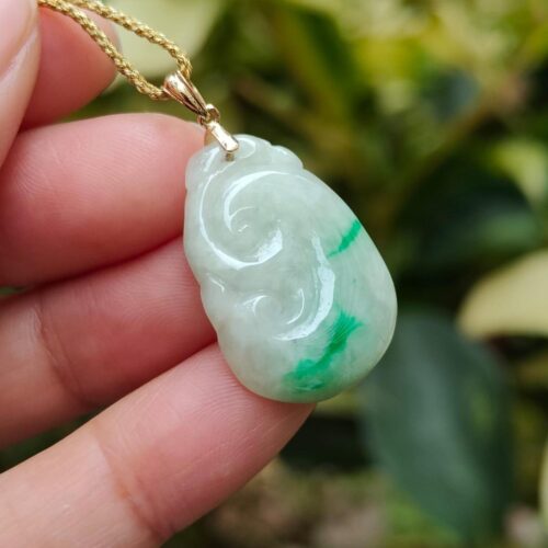 a hand holding a jade pendant