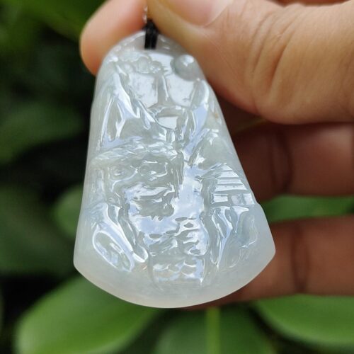 une main tenant un pendentif en jade