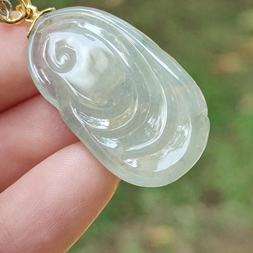 a hand holding a jade pendant