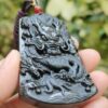 a hand holding a black dragon pendant