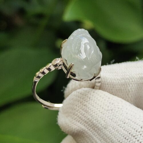 a hand wearing a glove holding a white ring with a carved stone