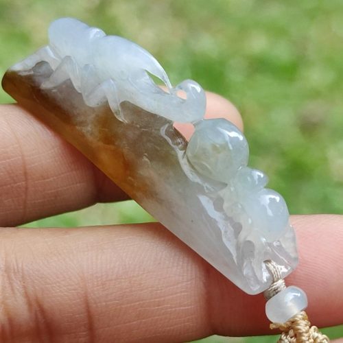 a hand holding a jade pendant