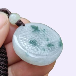 a hand holding a jade pendant