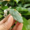 une main tenant un pendentif en jade
