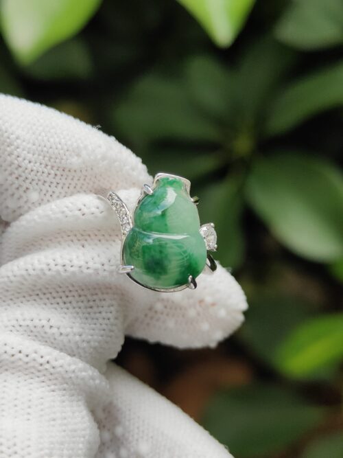 a hand wearing a white glove with a green stone ring