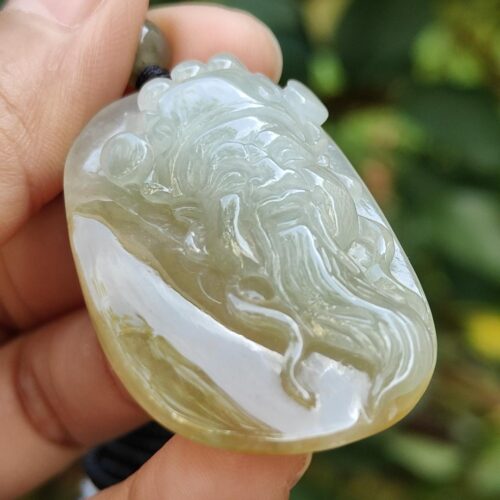 a hand holding a jade pendant