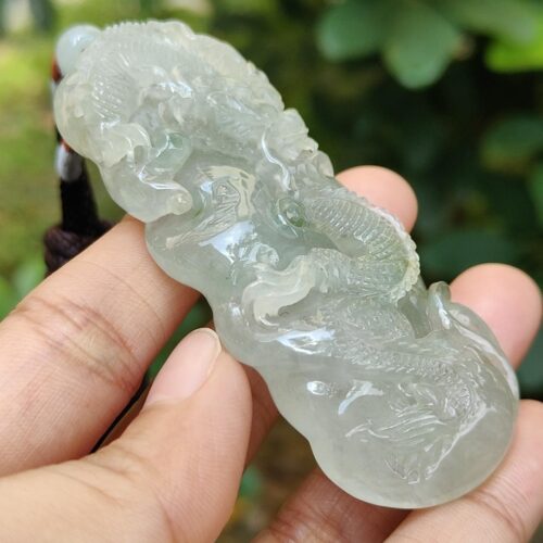 une main tenant un pendentif en jade