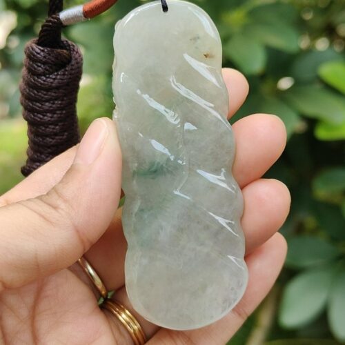 une main tenant un pendentif en jade