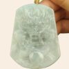a hand holding a jade pendant