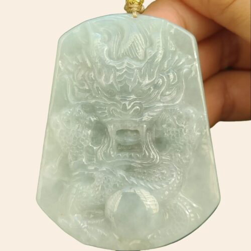 a hand holding a jade pendant