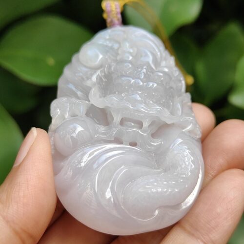 a hand holding a jade pendant