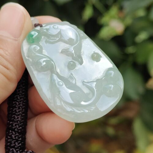a hand holding a jade pendant