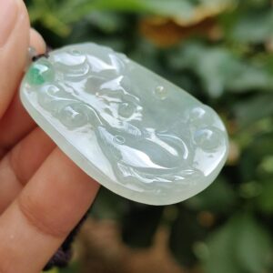 a hand holding a jade pendant