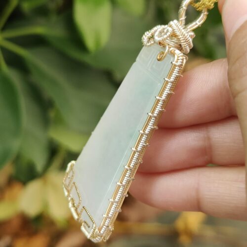 une main tenant un pendentif en jade