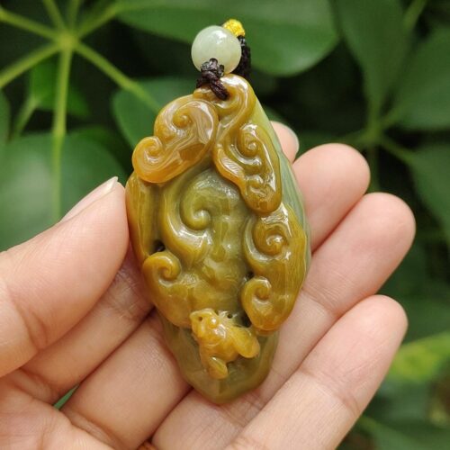 une main tenant un pendentif en jade