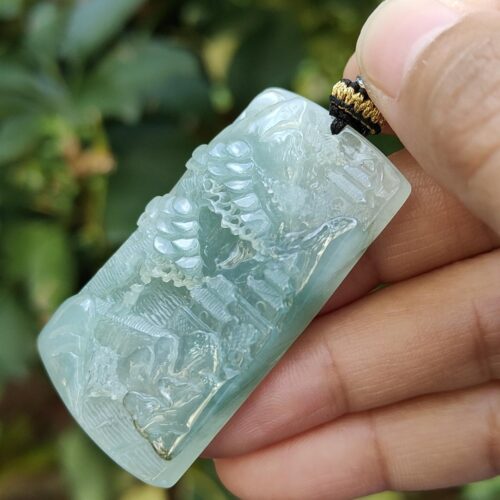 a hand holding a jade pendant