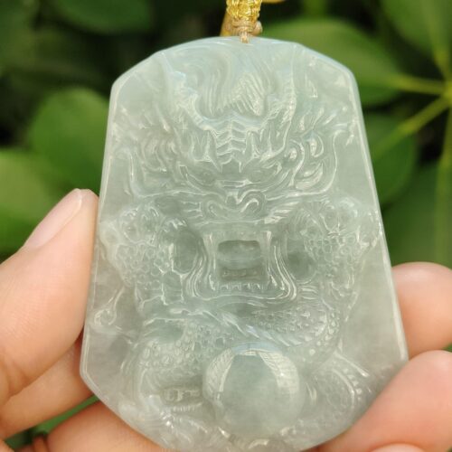 a hand holding a jade pendant