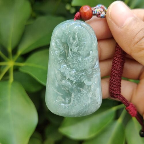 une main tenant un pendentif en jade