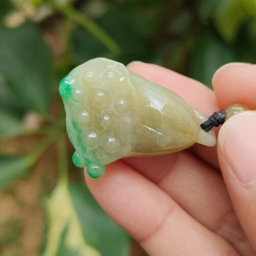 ஜேட் பதக்கத்தை வைத்திருக்கும் ஒரு கை