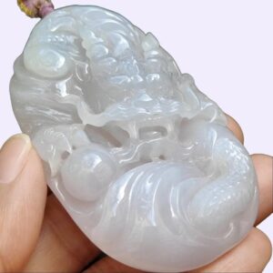 a hand holding a jade pendant