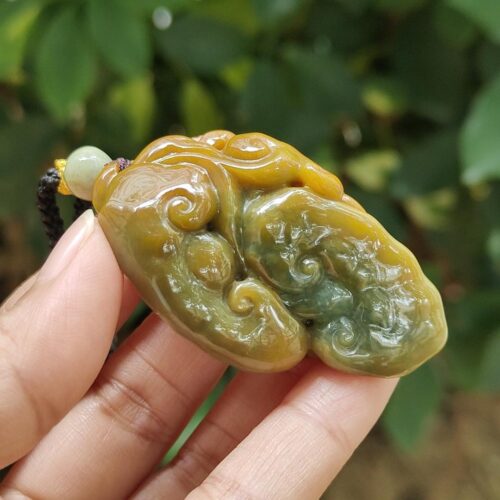 une main tenant un pendentif en jade