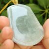 a hand holding a jade pendant