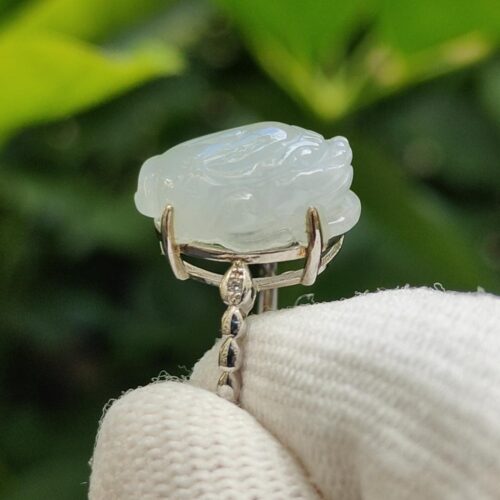 a hand holding a white gloved finger with a jade pendant