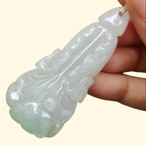 a hand holding a jade pendant