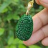 a hand holding a green pendant
