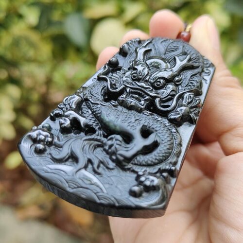 a hand holding a black dragon pendant