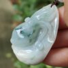 a hand holding a jade pendant