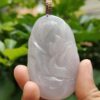 a hand holding a jade pendant