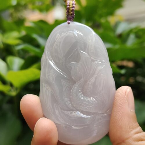 a hand holding a jade pendant