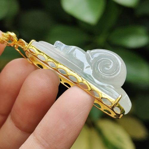 a hand holding a jade pendant
