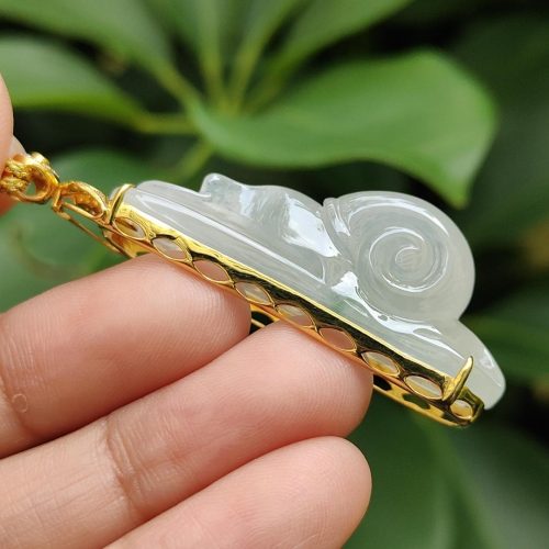 a hand holding a jade pendant