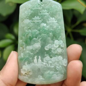 a hand holding a jade pendant