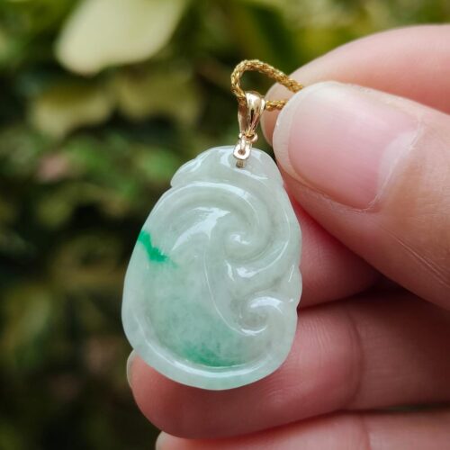 a hand holding a jade pendant