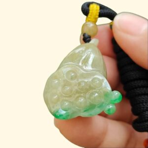 a hand holding a jade pendant