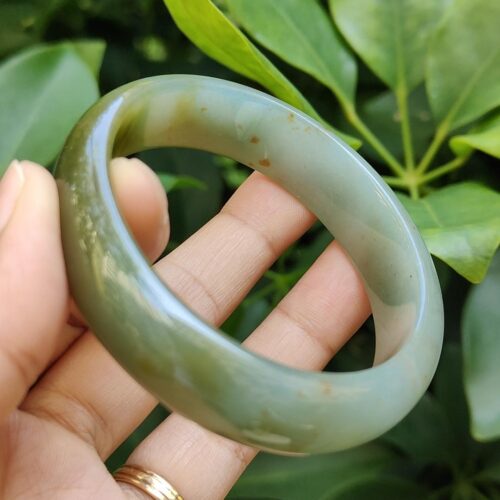 a hand holding a jade bracelet