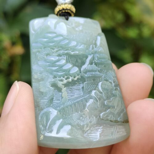 a hand holding a jade pendant