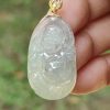 a hand holding a jade pendant