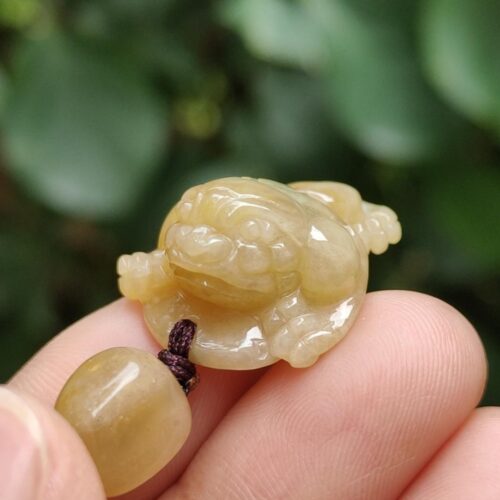 một bàn tay cầm một mặt dây chuyền ngọc bích