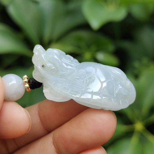 a hand holding a jade turtle necklace
