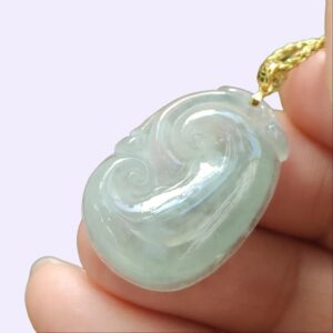 uma mão segurando um pingente de jade