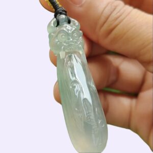 a hand holding a jade pendant
