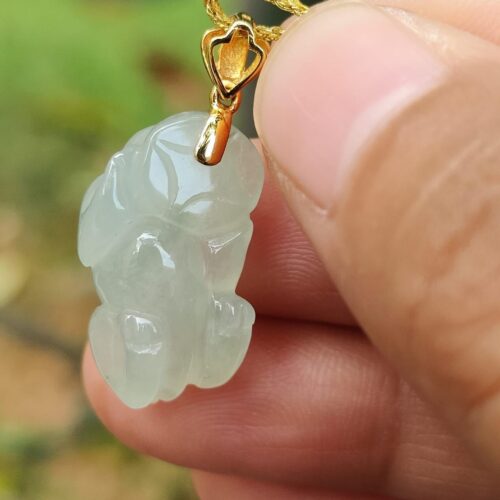 une main tenant un pendentif en jade