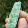 a hand holding a jade pendant