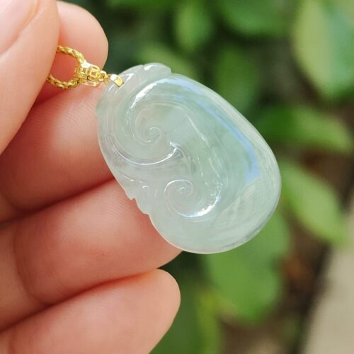 một bàn tay cầm một mặt dây chuyền ngọc bích