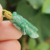 a hand holding a green insect pendant - Cicada